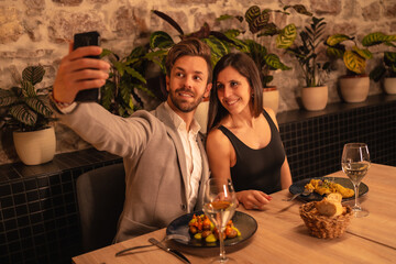 Lifestyle, a young couple in love in a restaurant, having fun dining together, celebrating Valentine's Day, taking a souvenir selfie