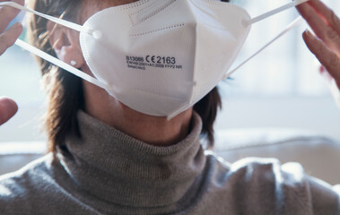 Corona Schutzmaske / FFP2 Atemschutzmaske / Frau / Altenpflege / Maske aufsetzen