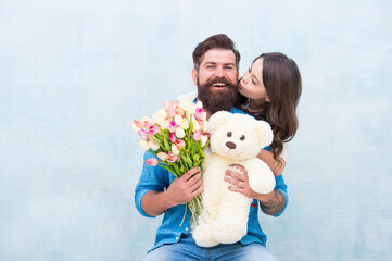 Fototapeta na wymiar happy family of father and daughter embrace with spring tulip flower bouquet and teddy bear toy, fathers day