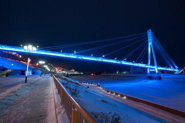 Tyumen, Russia, December 27, 2020: Pedestrian bridge on the embankment at night, in winter