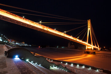 Tyumen, Russia, December 27, 2020: Pedestrian bridge on the embankment at night, in winter
