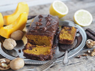 Festive homemade chocolate pumpkin long rectangular cupcake glazed with chocolate. Wooden table.