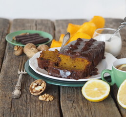 Festive homemade chocolate pumpkin long rectangular cupcake glazed with chocolate. Wooden table.