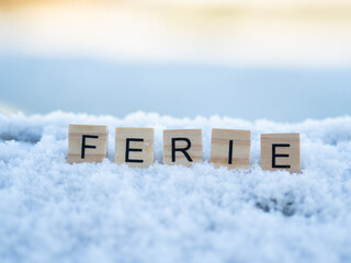 ferie - napis z drewnianych kostek, ułożony w śniegu, czas wolny, przerwa zimowa od szkoły, język polski  