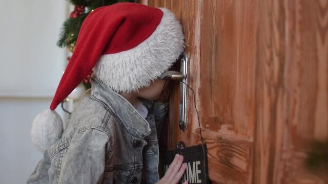 A young boy is waiting for the new year, Santa Claus. Peeps through the keyhole of the door.