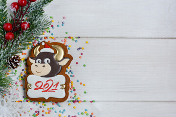 Gingerbread in the form of a bull, a Christmas tree with a pine cone and berries on a white wooden background. Happy new year 2021! Copy space for text