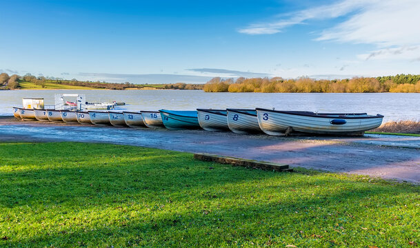 A line of rowing boats on the shoreline of  Pitsford Reservoir, UK on a sunny day