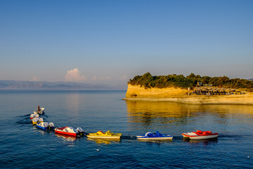 Fototapeta premium A small boat tugging a line of colorful catamarans