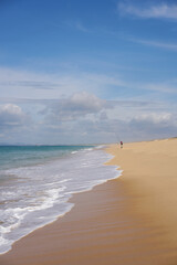 Fisherman fishing on a Comporta empty beach with ocean waves on the sand in Portugal
