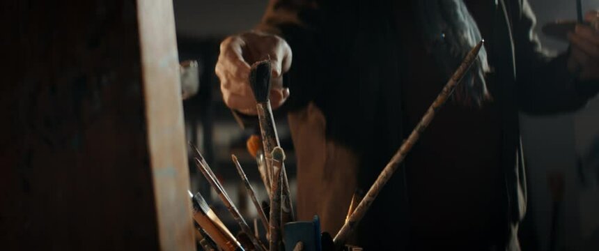 CU Portrait of senior middle eastern artist working on his painting in his garage studio. COVID-19 self isolation new hobbies concept. Shot with 2x anamorphic lens