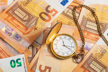 Euro bills and pocket watch