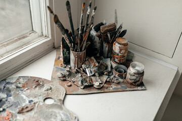 Heavy used artist's palette with brushes on white background