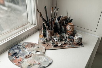 Heavy used artist's palette with brushes on white background