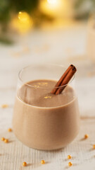 Traditional winter drink eggnog with cinnamon stick. Vertical orientation.