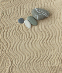 white and gray Zen stones on beige sand with abstract wave patterns. The concept of harmony, balance and meditation, spa, relaxation.