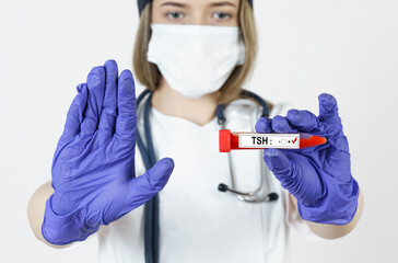 The doctor holds in his hands a test tube with blood tests for the TSH, with the other hand he makes a gesture - stop.