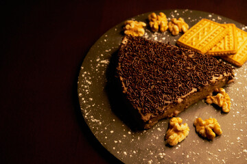 Portion of chocolate cake with chocolate chips, almonds and cookies