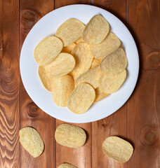 potato chips on a white plate on a wooden background. copy space.