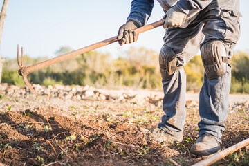 unrecognizable man tilling the land in the field