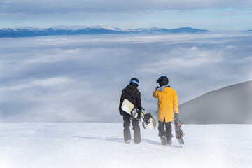 
Two snowboarders talking while  walking on the mountain