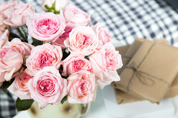 Rose White Pink O'hara. a bouquet of pink roses in round vase, wrapped gifts, books
