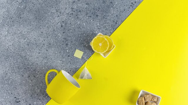 Creative stop motion of Ultimate Gray and Illuminating trending color tea food background. Tea, lemon, cup and spoon on gray and yellow table surface.