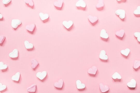 White and pink heart shaped marshmallows on a pink background with copy space