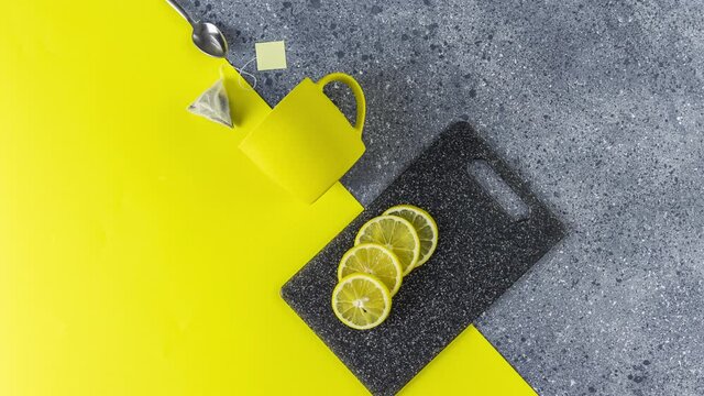 Creative stop motion of Ultimate Gray and Illuminating trending color tea food background. Tea, lemon, cup and spoon on gray and yellow table surface.