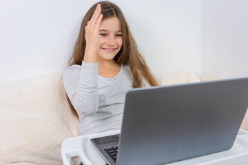 Portrait of attractive cute happy smiling girl 6-7 old sitting using laptop indoor white background distance learning