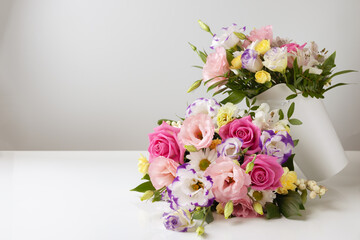 mock up two bouquets of different sizes of roses, daisies, lisianthus, chrysanthemums, unopened buds in a white paper box on a white background, one bouquet lies on top of the other.