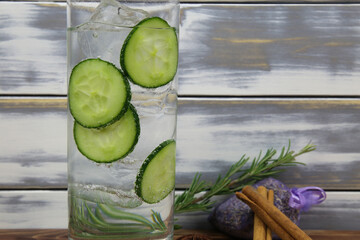Close up of isolated cocktail glass with gin tonic cucumber slices, cinnamon, lavender, rosemary,...