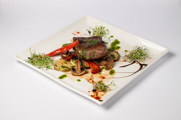 Veal mignon fillet with grilled vegetables on a white background