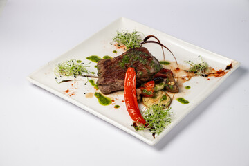 Veal mignon fillet with grilled vegetables on a white background