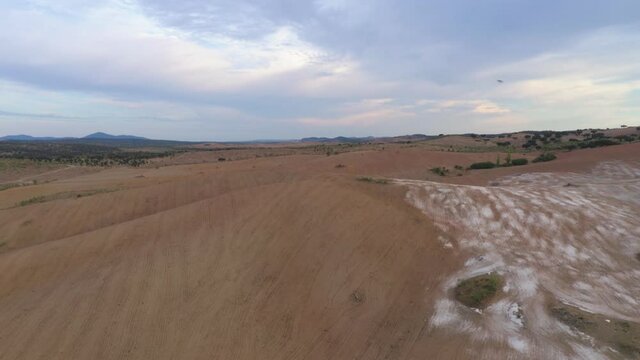 Drone aerial panorama of a desert like hill landscape with marble stones dust at sunset in Terena, Portugal