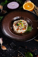 Basmati rice with fried carrots, onions, mushrooms, broccoli vegetables in butter on a dark background