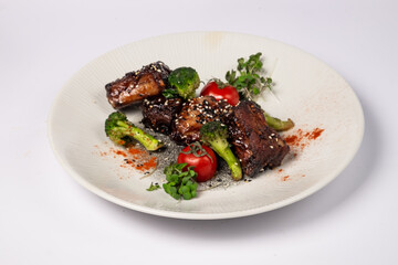 Grilled pork ribs in honey glaze with tomatoes and broccoli on a white background