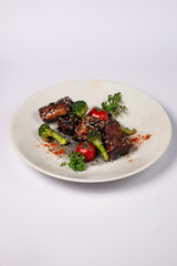 Grilled pork ribs in honey glaze with tomatoes and broccoli on a white background