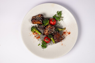 Grilled pork ribs in honey glaze with tomatoes and broccoli on a white background