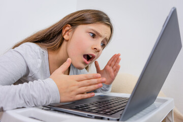Emotional portrait of attractive cute girl 6-7 old sitting using laptop indoor white background...