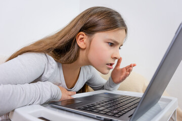 Emotional portrait of attractive cute girl 6-7 old sitting using laptop indoor white background...