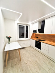 Small white kitchen interior. Modern minimalist apartment in white with black and wood elements. Hygge, Lagom.