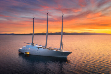 Aerial view of luxury yacht in blue sea at sunset in summer. Big modern sail boat. Top view of...