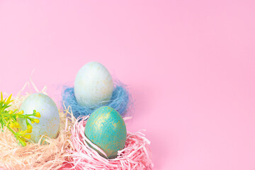 Three Easter eggs in a nest on a pink background.
