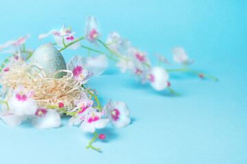 Fototapeta na wymiar Easter blue egg in a nest on a light blue background.