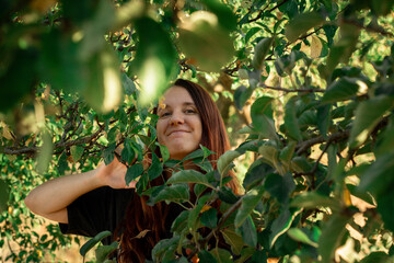 Redhead smiling girl looking through trees in nature
