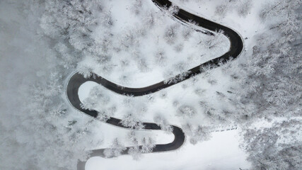mountain road with many curves through snowy forest