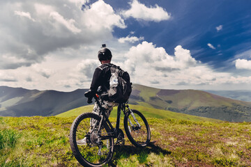 Obraz premium A young guy stands with a bicycle on top of a mountain