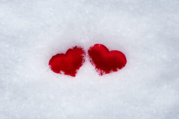 Fototapeta premium two little hearts in the snow. symbol of love and loyalty, Valentine's Day. Horizontal photo.