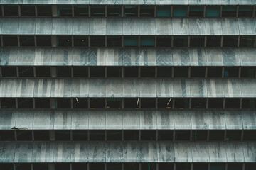 A horizontal texture of a greenish contemporary business office skyscraper facade with horizontal rows of windows and marble separators making a pattern together