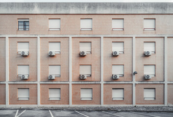 A texture of a real four-story house elevation with a row of identical windows and air conditioning...